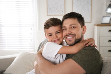 Photo of Father and his son on sofa in living room. Adoption concept
