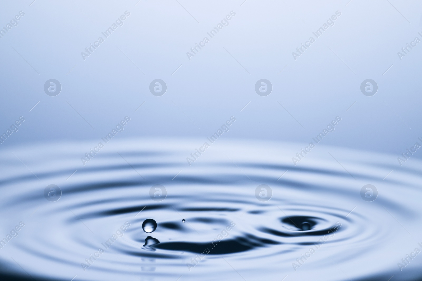 Photo of Splash of clear water with drops on light grey background, closeup