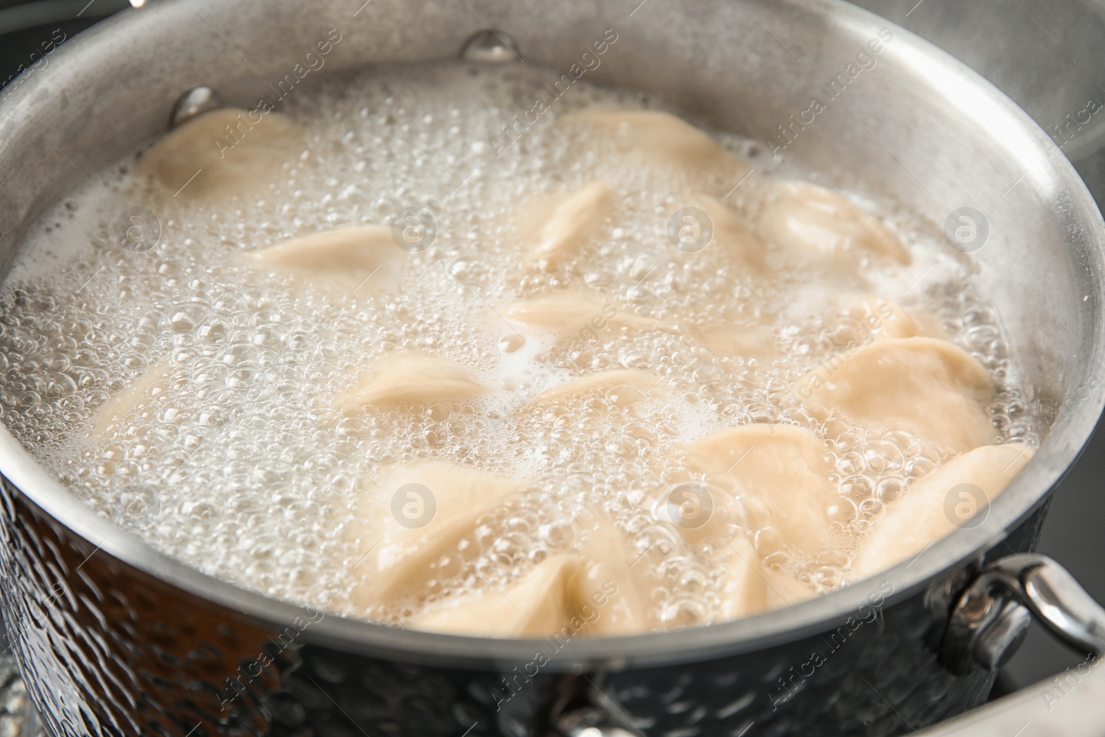 Photo of Closeup of metal stewpan with boiling water and dumplings. Home cooking