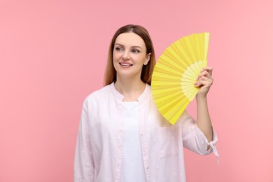 Photo of Happy woman with yellow hand fan on pink background