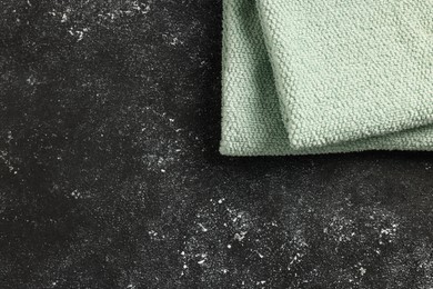 Photo of Soft terry towel on black textured background, top view. Space for text