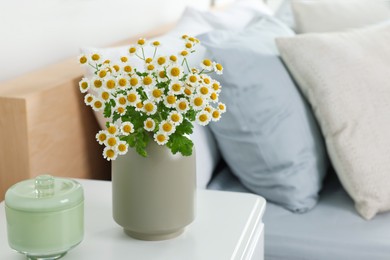 Photo of Beautiful bouquet of chamomile flowers on white nightstand in bedroom, space for text. Interior element