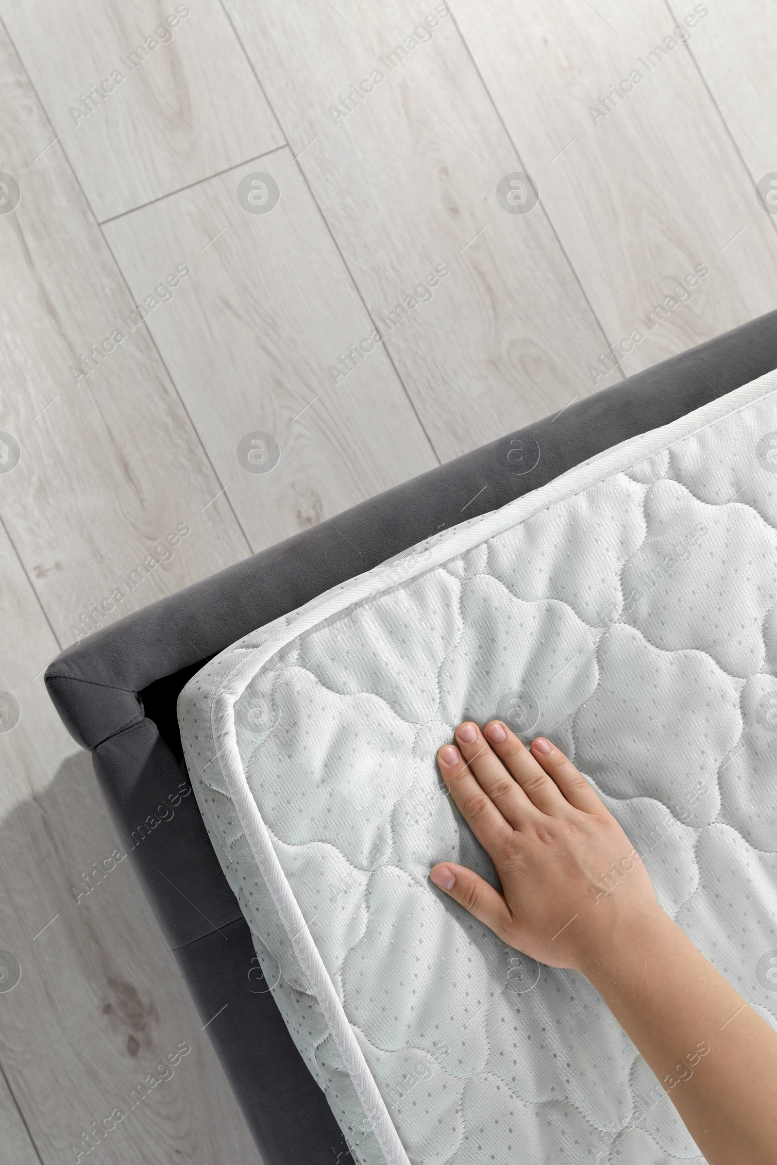 Photo of Woman touching soft light green mattress on bed, top view