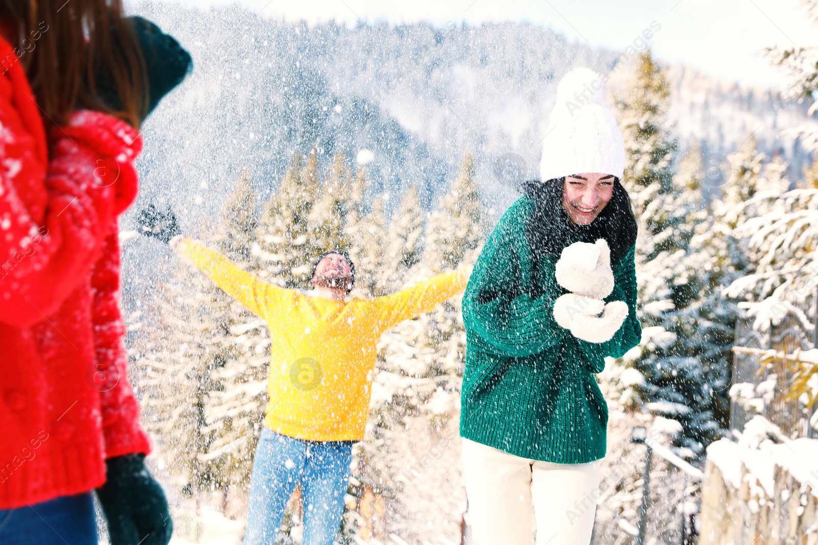 Photo of Happy friends playing snowballs outdoors. Winter vacation