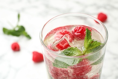 Photo of Glass of refreshing drink with raspberry and mint on table, closeup view. Space for text