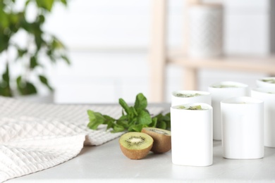 Photo of Cups for homemade yogurt and fresh kiwi on table in kitchen. Recipe for multi cooker