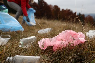 Woman collecting garbage in nature, focus on plastic trash