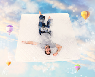 Image of Sweet dreams. Blue cloudy sky with hot air balloons around young man