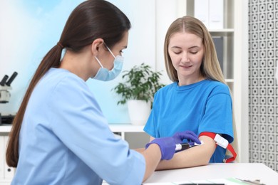 Laboratory testing. Doctor taking blood sample from patient at white table in hospital