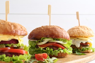 Photo of Delicious vegetarian burgers served on wooden board