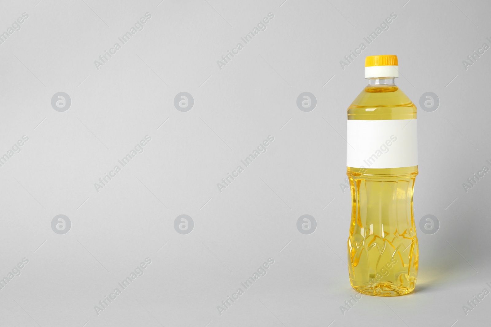 Photo of Bottle of cooking oil on light grey background. Space for text