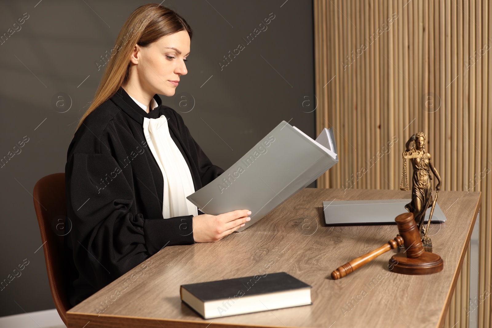 Photo of Judge with folder working at table in courtroom