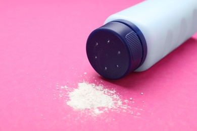 Photo of Bottle and scattered dusting powder on pink background. Baby cosmetic product