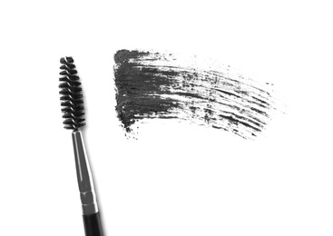 Photo of Applicator and black mascara smear for eyelashes on white background, top view