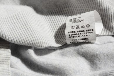 Photo of Clothing label with instruction on white garment, closeup