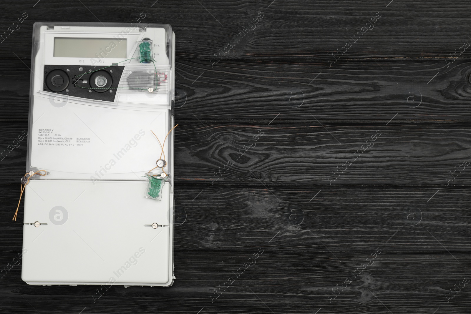 Photo of Electric meter on black wooden background, top view with space for text. Measuring device