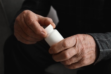 Senior man holding bottle with pills, closeup of hands