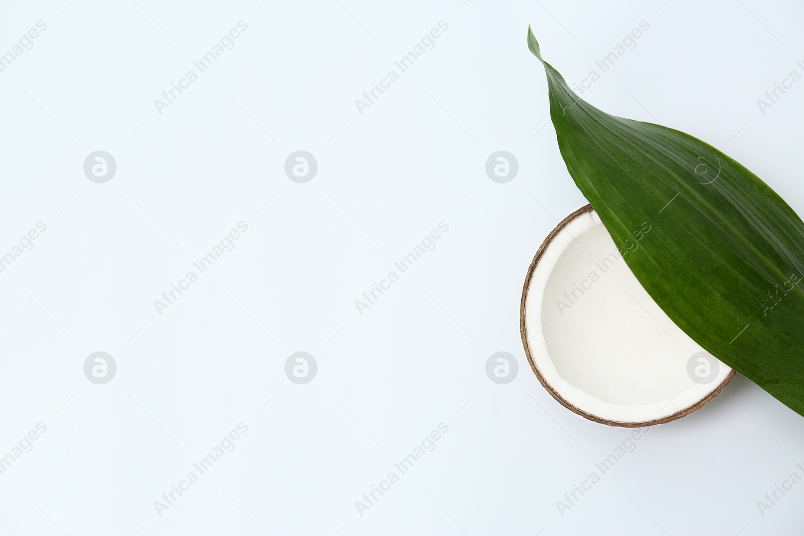 Photo of Half of fresh coconut and palm leaf on white background, top view