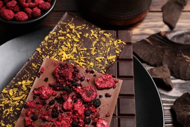 Photo of Chocolate bars with freeze dried fruits on wooden table, closeup