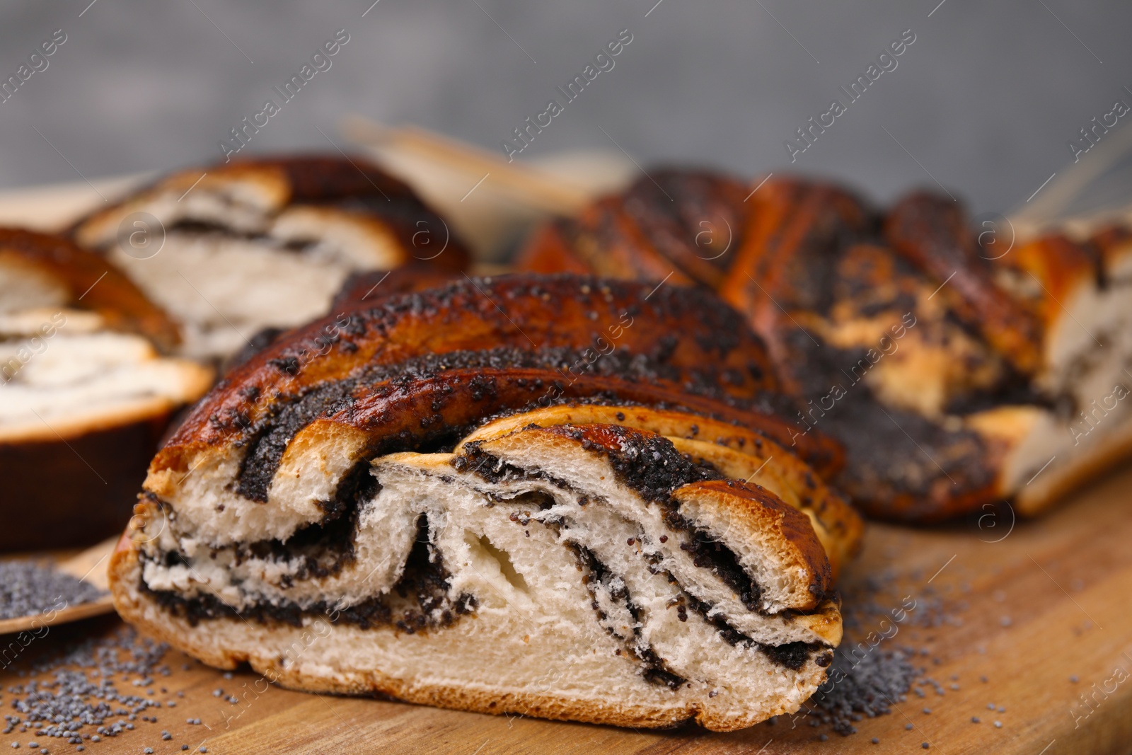 Photo of Cut poppy seed roll on wooden board, closeup. Tasty cake