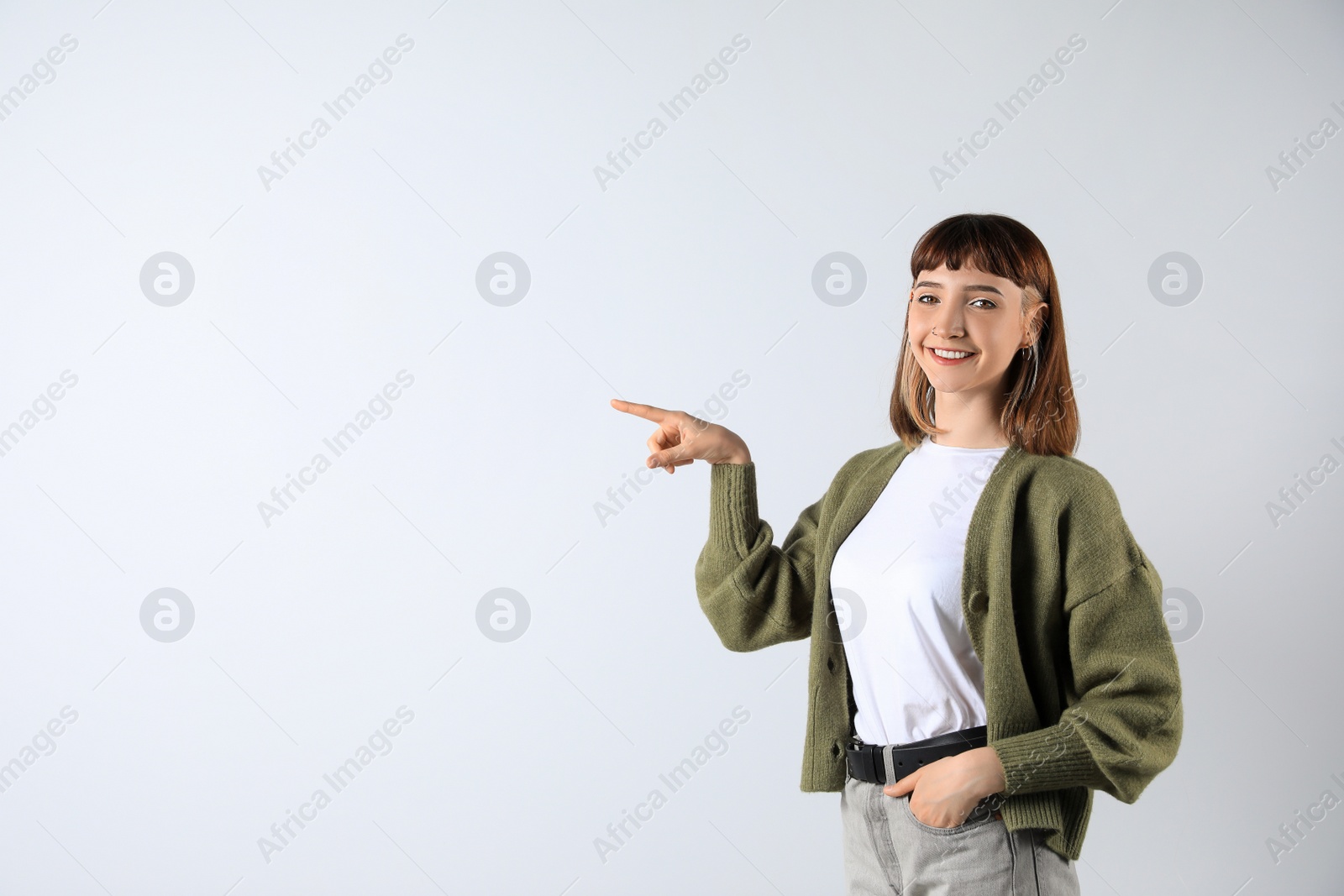 Photo of Beautiful young girl pointing on white background. Space for text