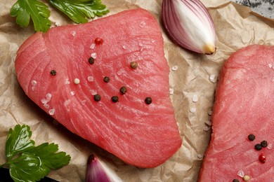 Photo of Raw tuna fillets with spices on parchment paper, top view