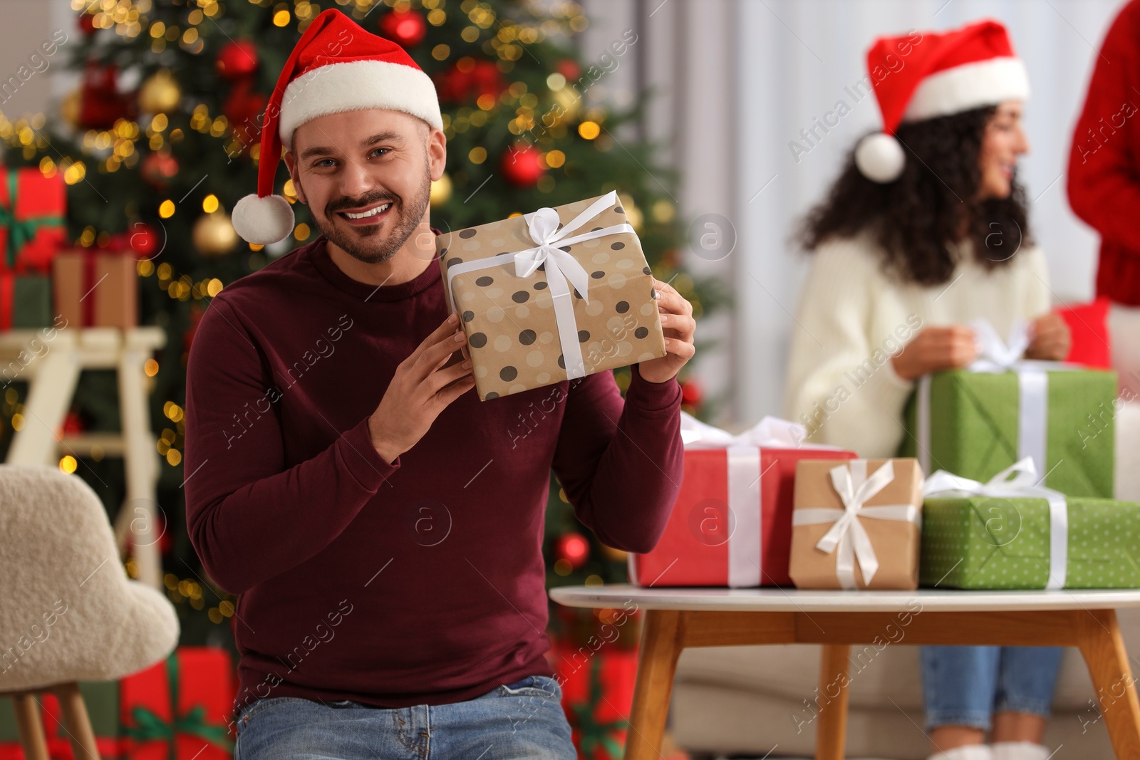 Photo of Christmas celebration in circle of friends. Happy man with gift box at home, selective focus