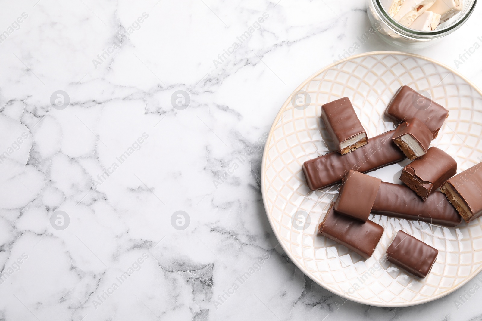 Photo of Tasty chocolate bars and nougat on white marble table, flat lay. Space for text