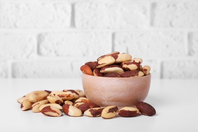 Photo of Tasty Brazil nuts on white table against brick wall