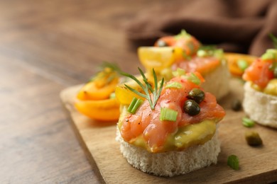 Photo of Tasty canapes with salmon served on wooden table, closeup. Space for text