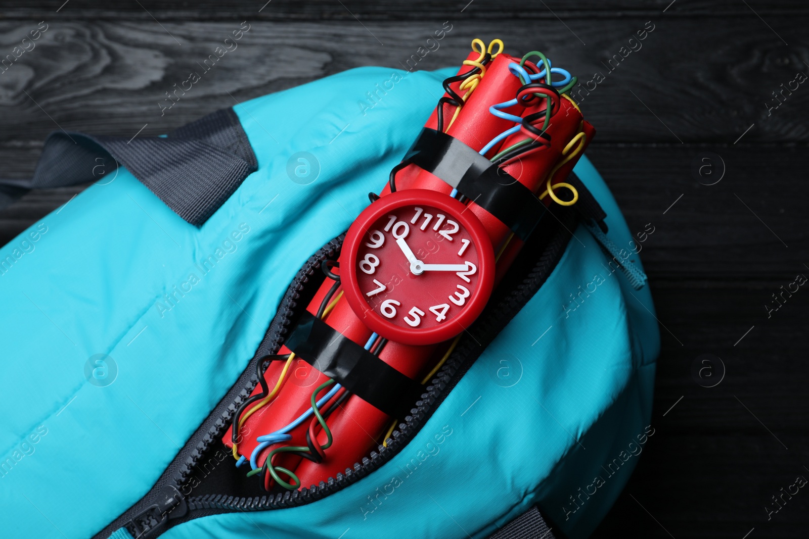 Photo of Blue sportive bag with dynamite time bomb on black wooden table, top view