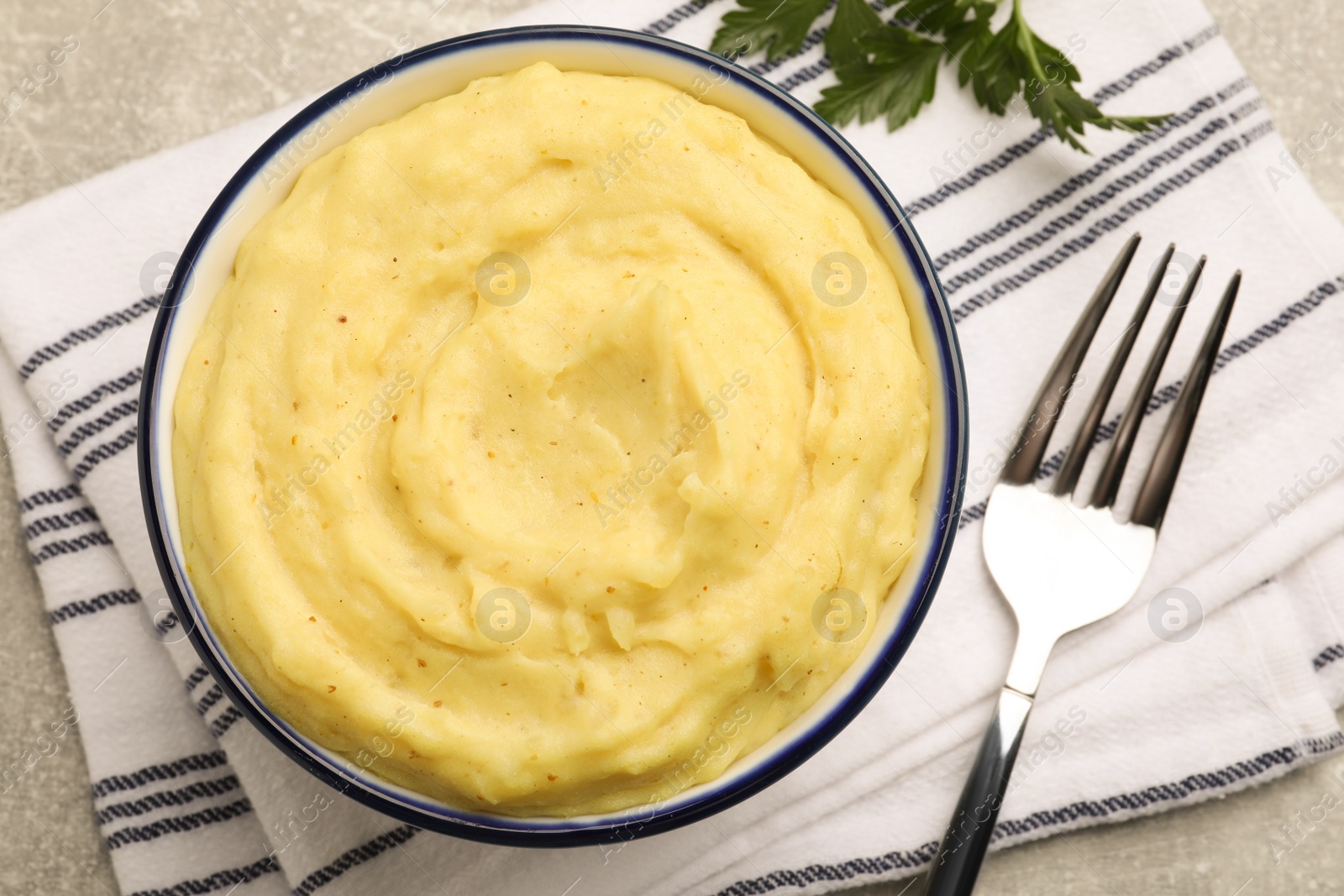 Photo of Bowl of tasty mashed potatoes served on grey table, flat lay