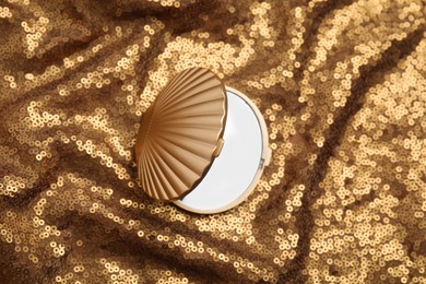 Photo of Bright cosmetic pocket mirror on gold fabric, top view