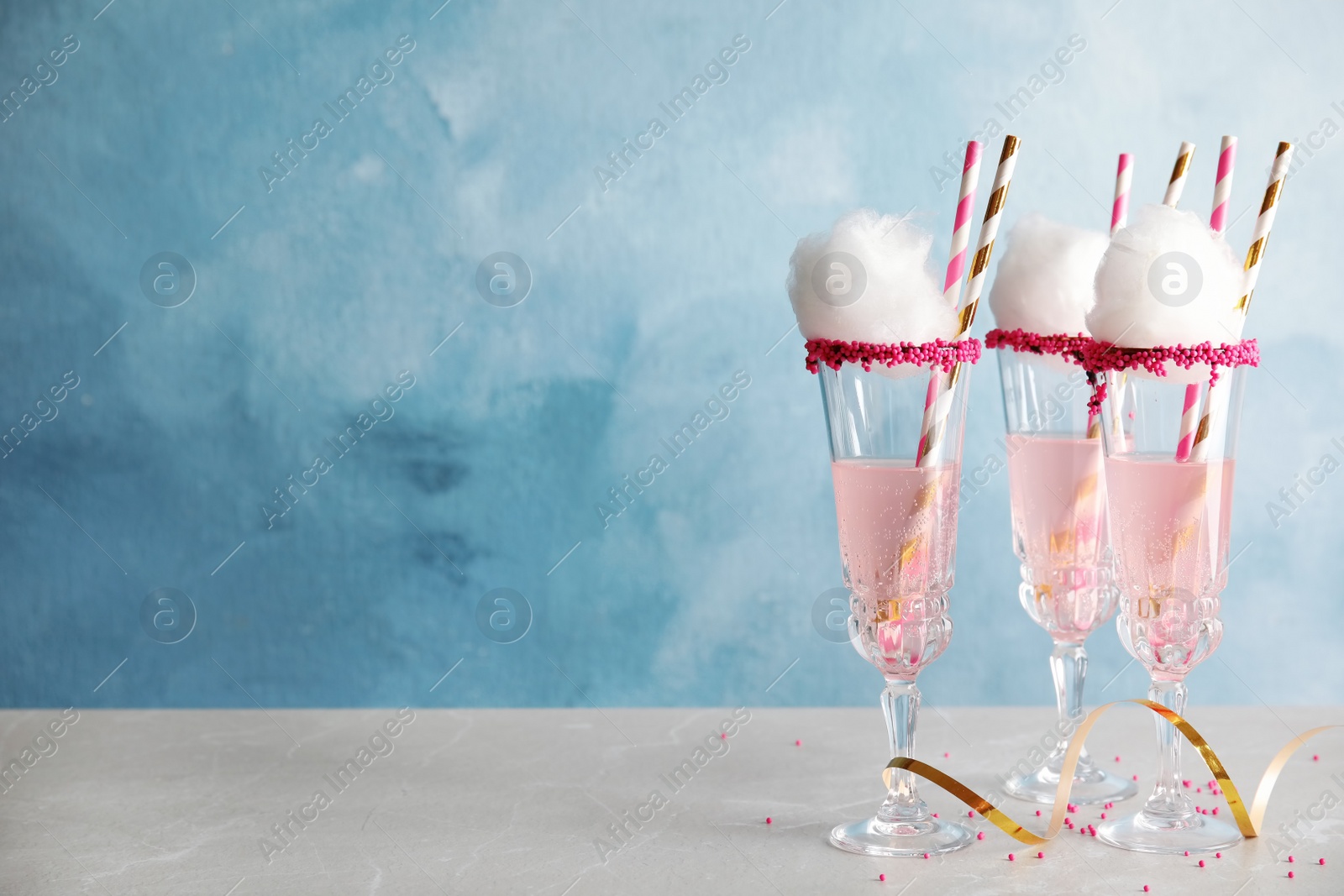 Photo of Cocktail with cotton candy in glasses on table. Space for text