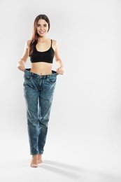 Photo of Attractive young woman with slim body wearing her old big jeans on white background. Space for text