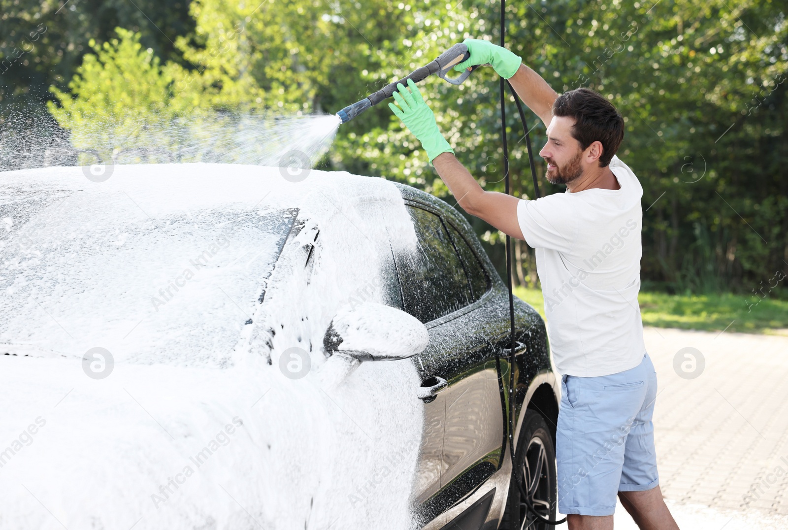 Photo of Man covering automobile with foam at outdoor car wash