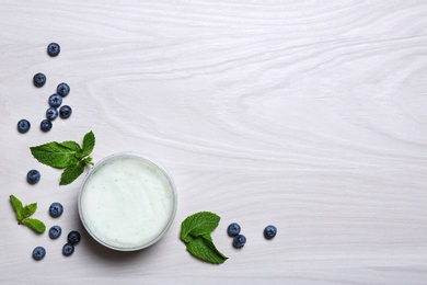 Photo of Flat lay composition with jar of body cream on light wooden background. Space for text