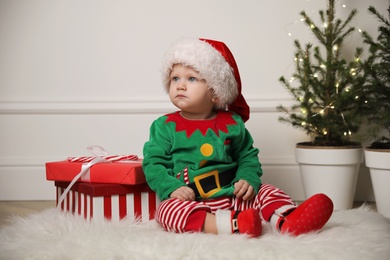 Baby in cute Christmas outfit with gifts at home