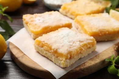 Tasty lemon bars with powdered sugar on table, closeup