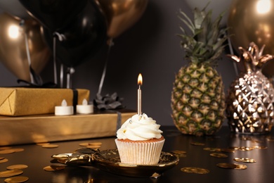 Photo of Cupcake with candle and blurred balloons on background