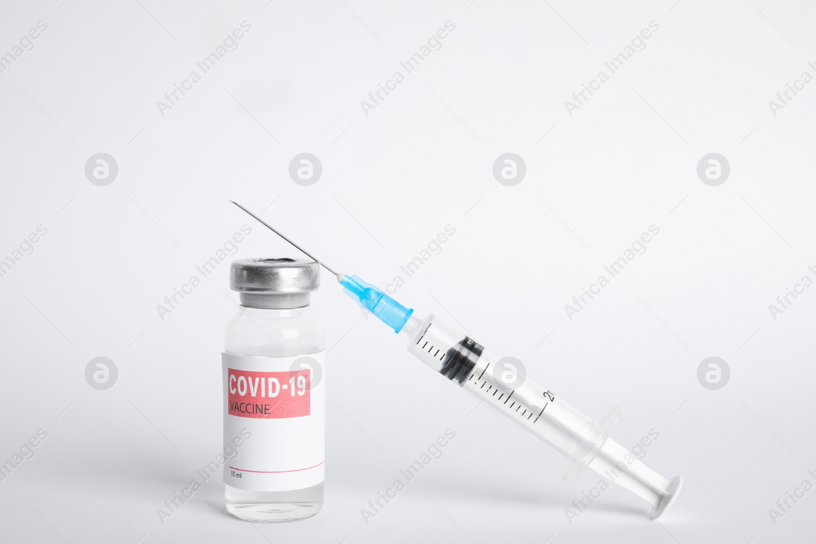 Photo of Vial with coronavirus vaccine and syringe on white background