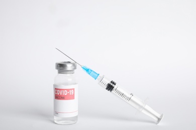 Photo of Vial with coronavirus vaccine and syringe on white background