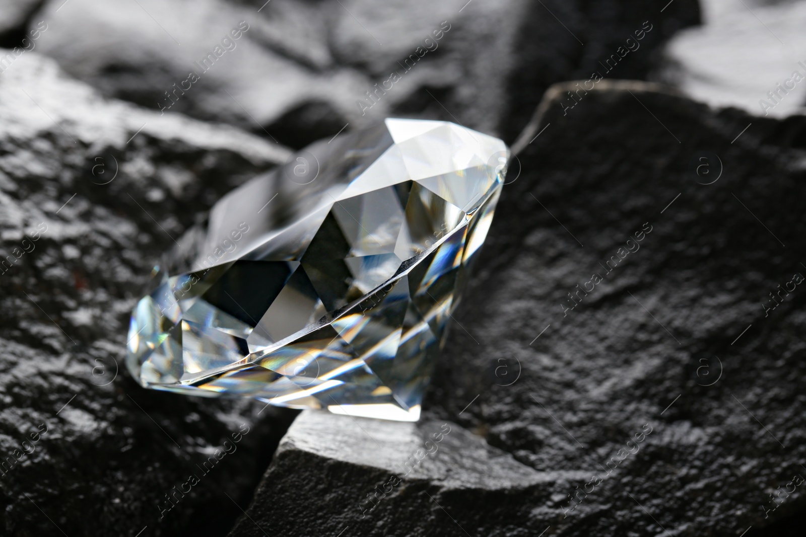 Photo of Beautiful shiny diamond on coal, closeup view