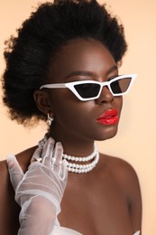 Photo of Fashionable portrait of beautiful woman with stylish sunglasses on beige background