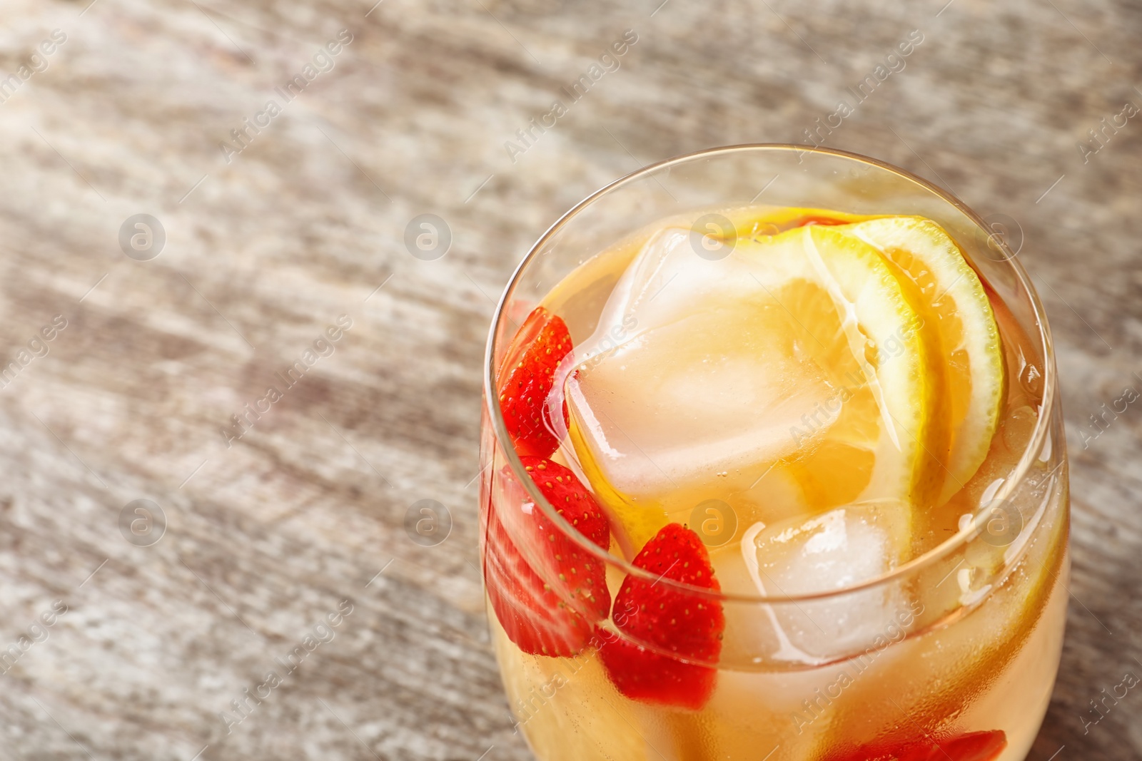 Photo of Natural lemonade with strawberries in glass on wooden table, closeup