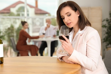 Photo of Woman with glass of wine at table in restaurant, space for text