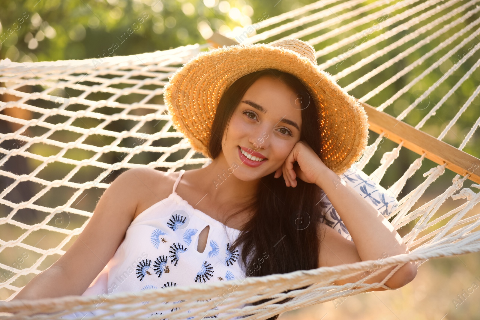 Photo of Young woman resting in comfortable hammock at green garden