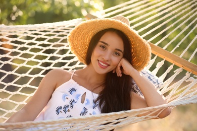 Young woman resting in comfortable hammock at green garden