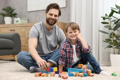 Happy dad and son playing with cubes at home