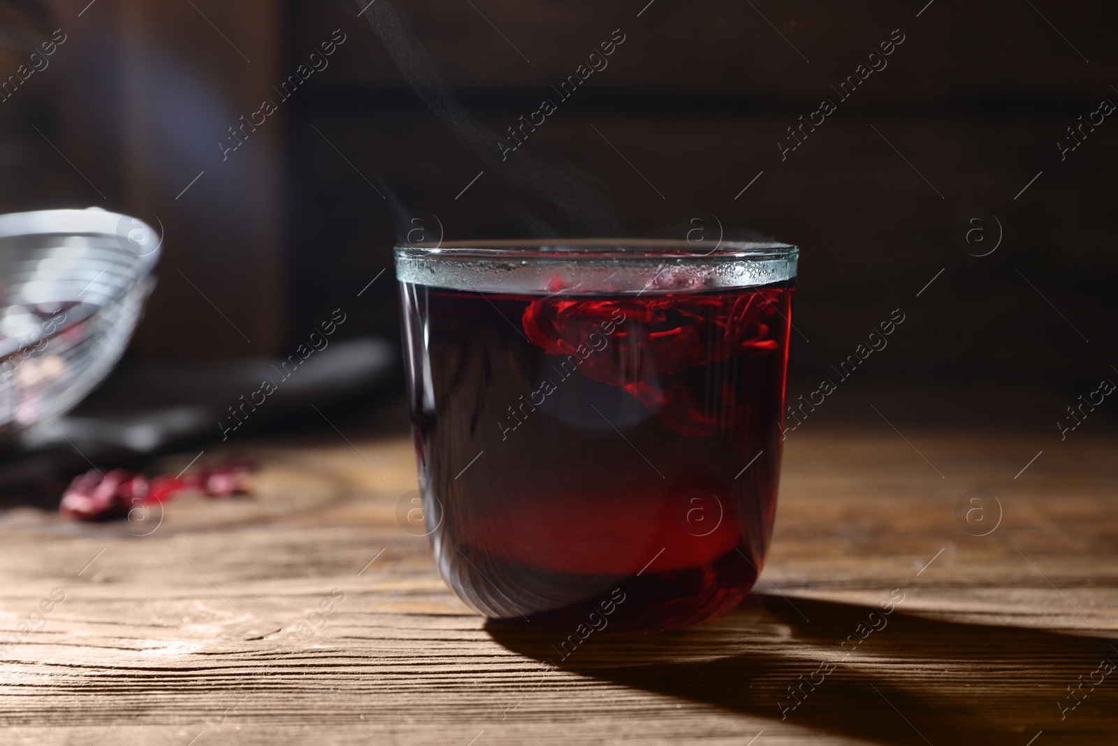 Photo of Delicious hibiscus tea in glass on wooden table, closeup